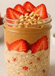 Jar of overnight oats layered with strawberries, peanut butter, and oats.